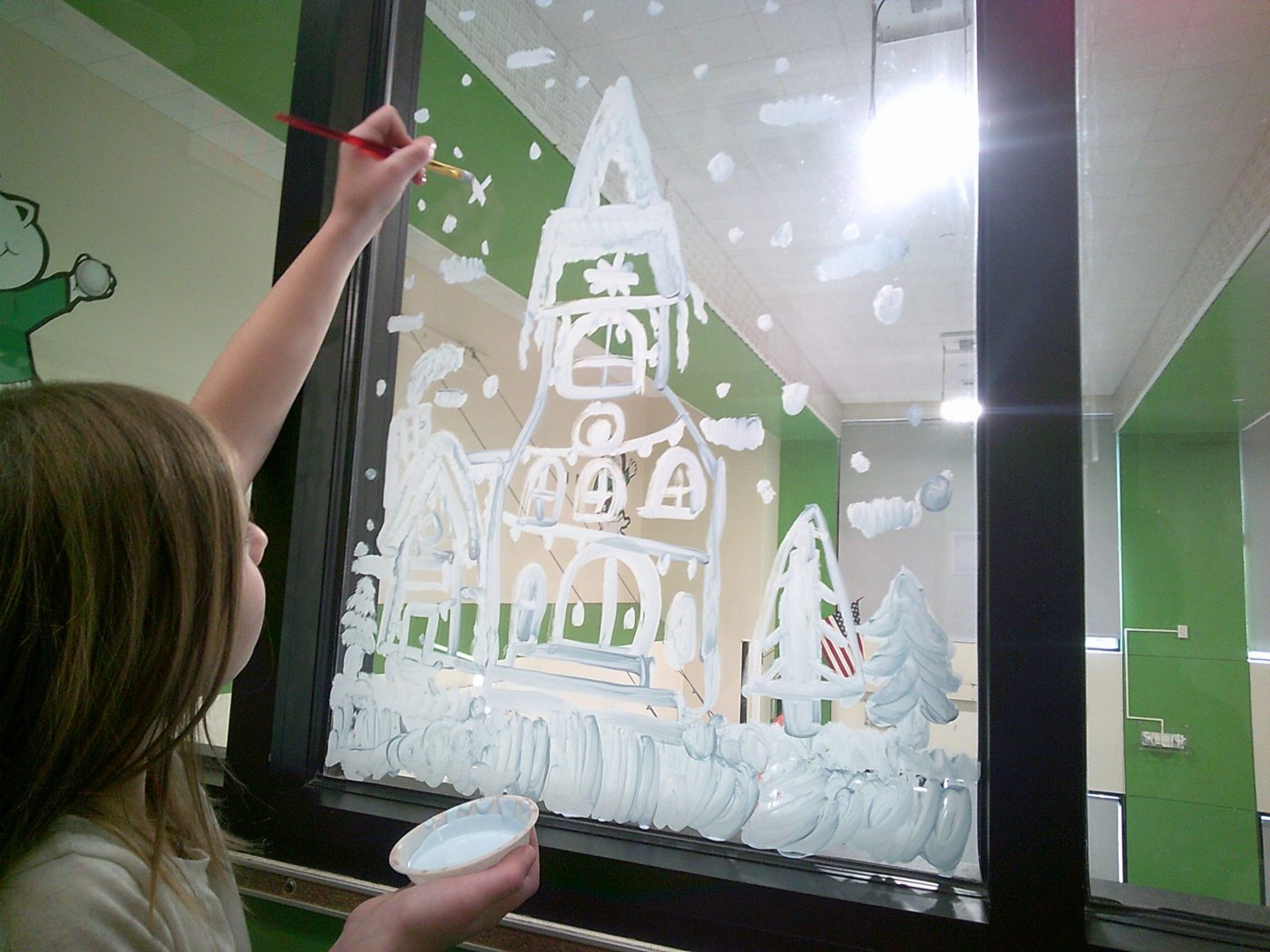 A student paints on the window during Art Club.