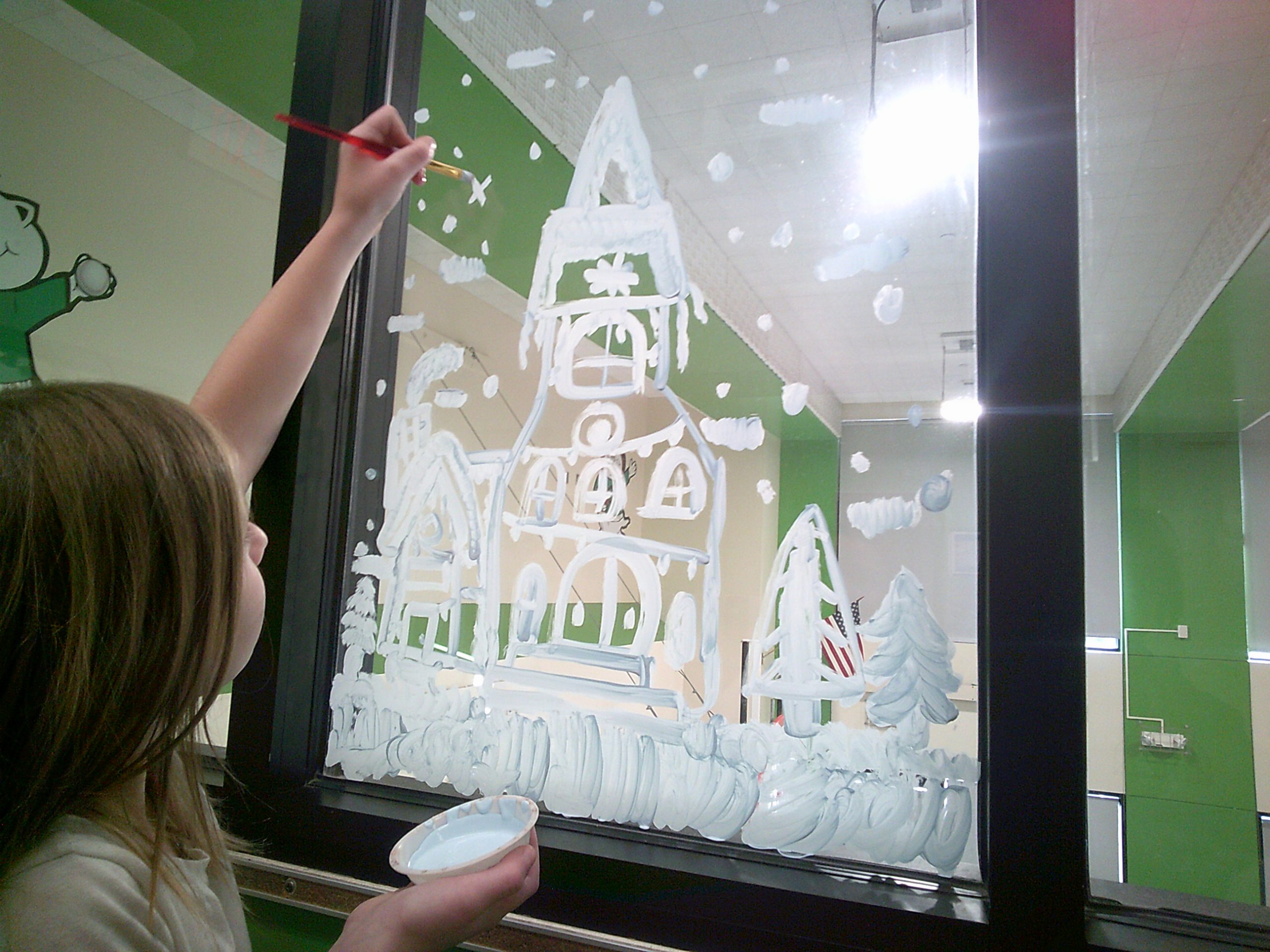 A student paints on the window during Art Club.
