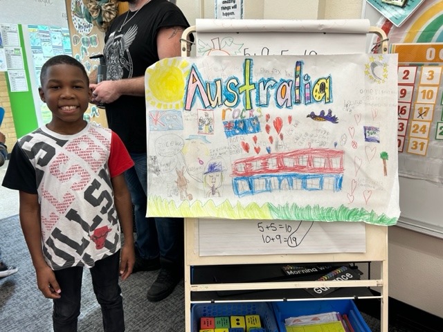 A student poses with his presentation at the 2nd Grade Celebration of Learning.